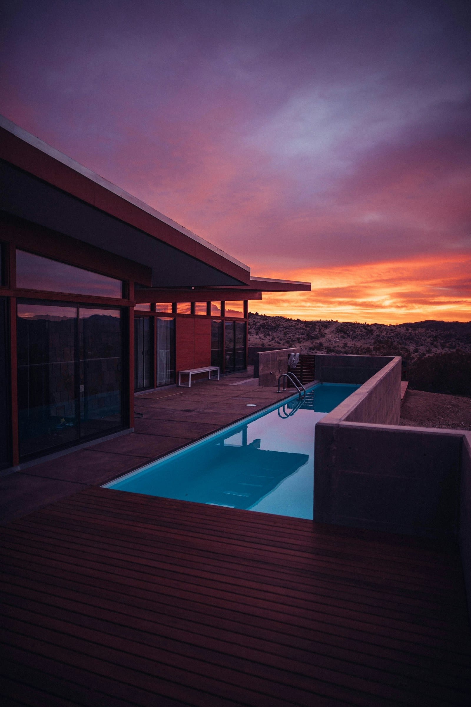 A swimming pool beside a contemporary home during golden hour