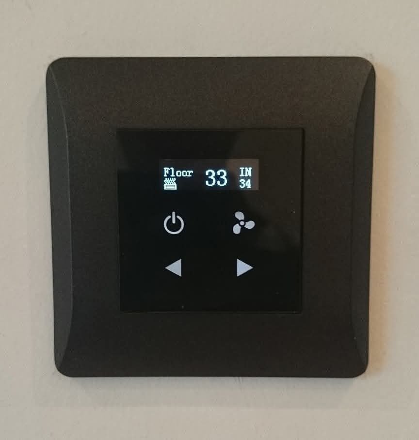 A dark textured climate control panel showing floor temperature