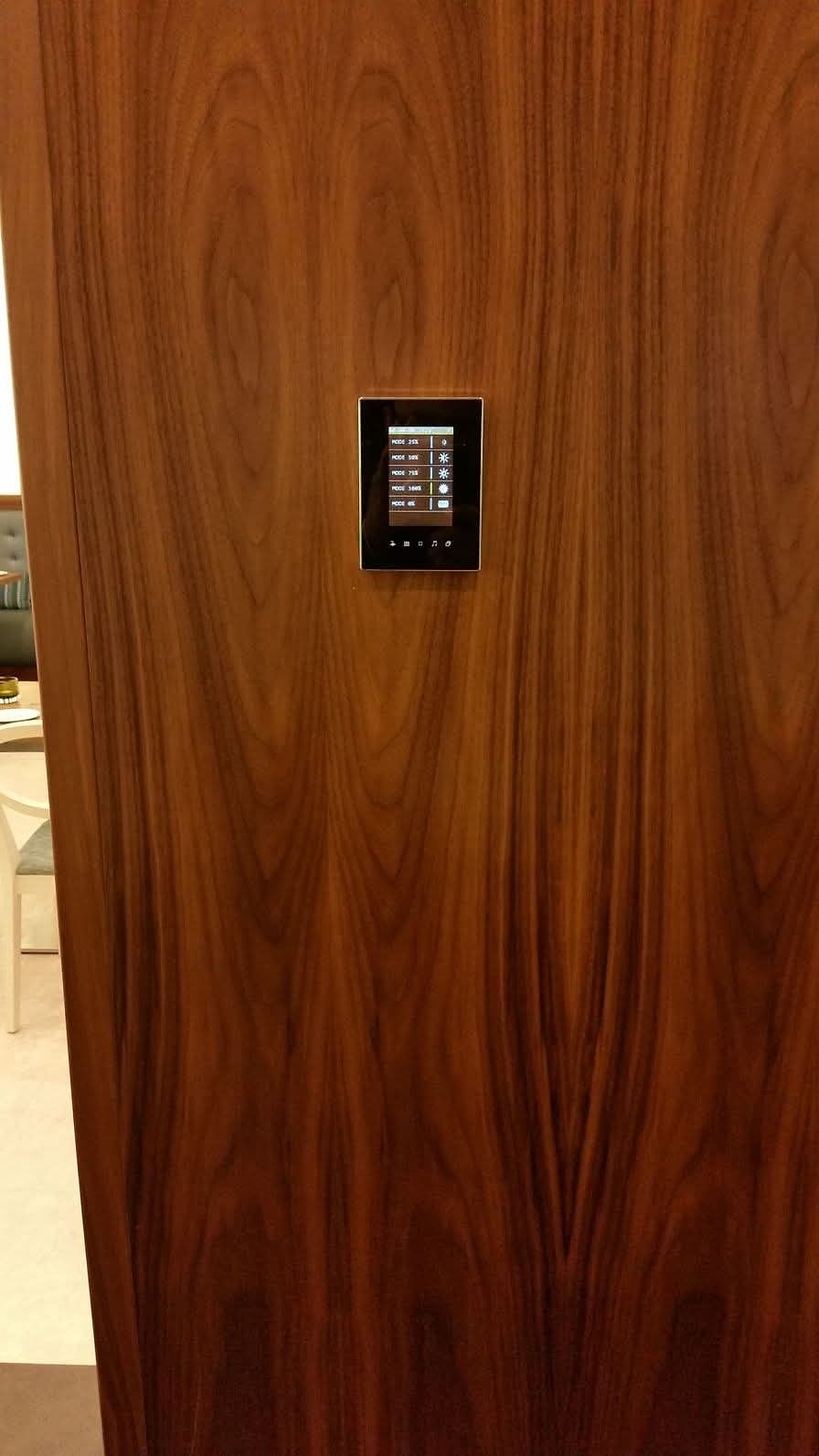 A small lighting control panel set flush into a walnut-veneered wall